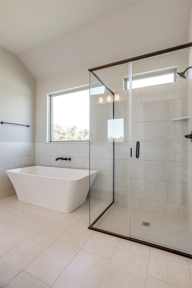 bathroom with tile walls, independent shower and bath, tile patterned flooring, and lofted ceiling