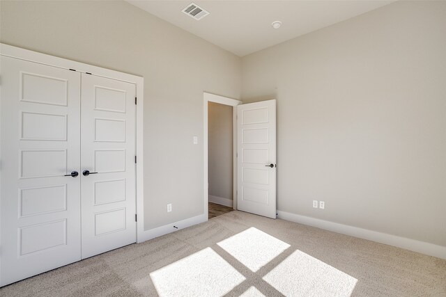 unfurnished bedroom with light carpet and a closet