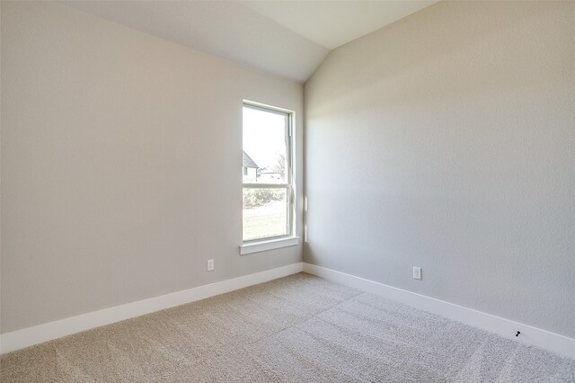 carpeted empty room featuring vaulted ceiling