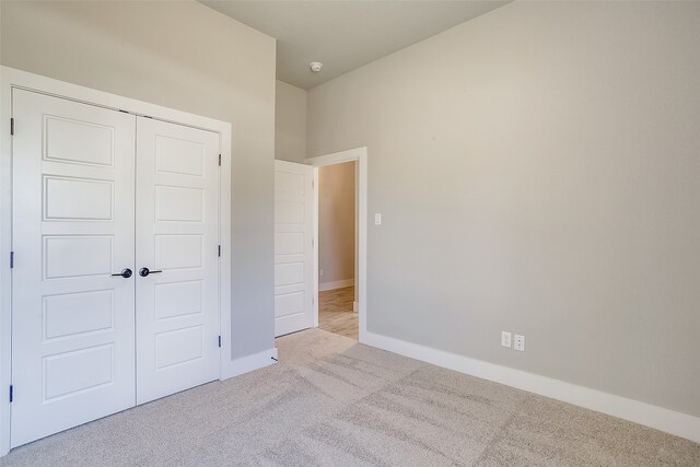 unfurnished bedroom with light carpet and a closet