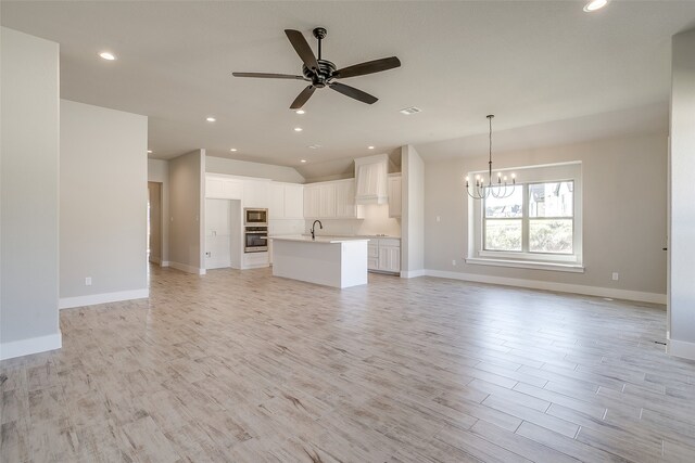 unfurnished living room featuring sink, light hardwood / wood-style floors, and ceiling fan with notable chandelier