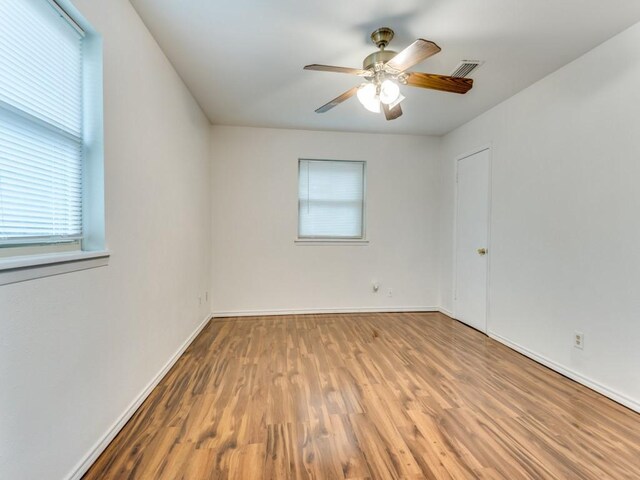 spare room with ceiling fan, a wealth of natural light, and hardwood / wood-style flooring