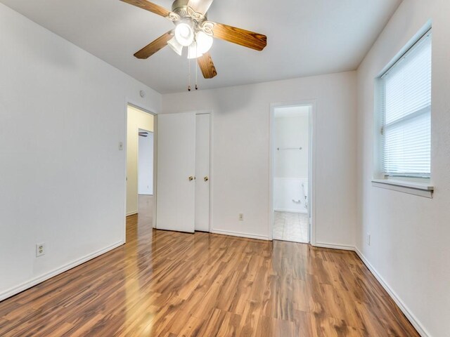 unfurnished bedroom with hardwood / wood-style floors, ensuite bathroom, and ceiling fan