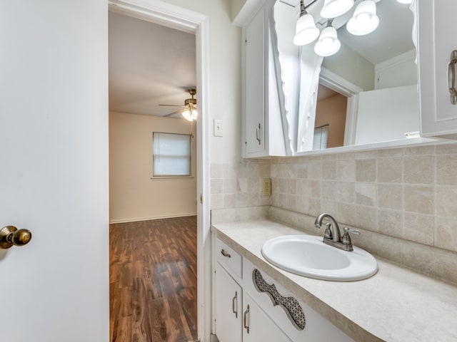 bathroom with ceiling fan with notable chandelier, vanity, wood-type flooring, and decorative backsplash