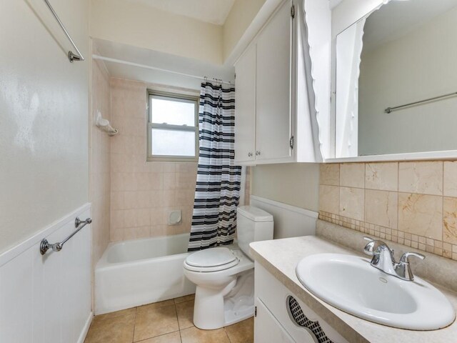 full bathroom with vanity, backsplash, toilet, tile patterned floors, and shower / bath combo with shower curtain