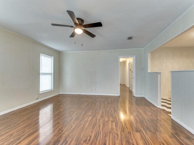 empty room with crown molding, dark wood-type flooring, and ceiling fan