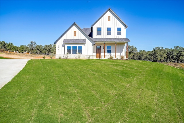 modern farmhouse with a front yard and covered porch