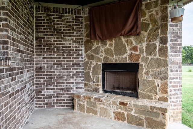 details with an outdoor stone fireplace and concrete flooring