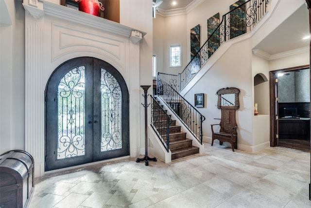 foyer with a high ceiling, crown molding, and french doors