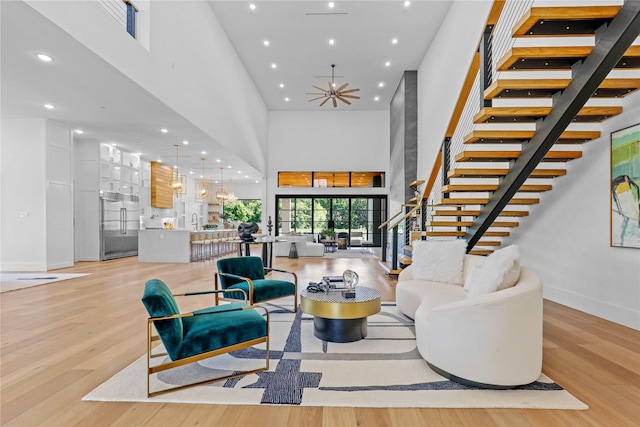 living room with a high ceiling, light wood-type flooring, ceiling fan, and sink