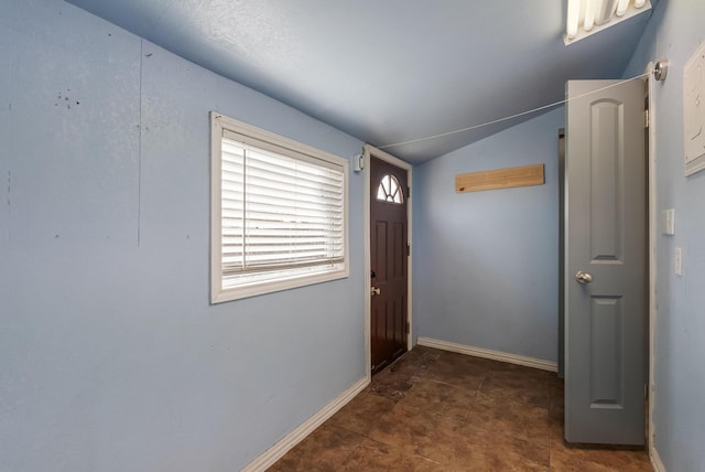 entryway with lofted ceiling and dark tile patterned flooring