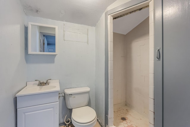 bathroom with vanity, tiled shower, a textured ceiling, and toilet