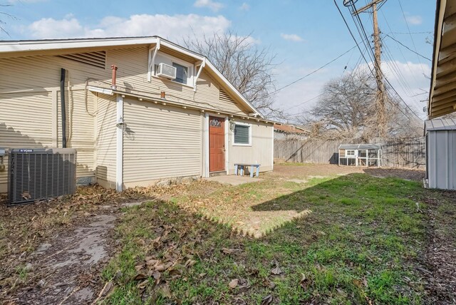 back of house with an outbuilding, central AC unit, and a lawn