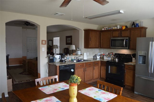 kitchen with black appliances, sink, light stone countertops, tasteful backsplash, and dark hardwood / wood-style flooring