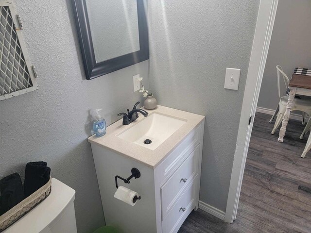 bathroom with vanity, toilet, and hardwood / wood-style flooring