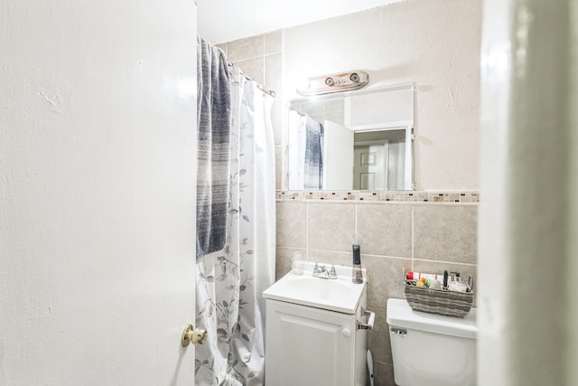 bathroom featuring toilet, walk in shower, vanity, tasteful backsplash, and tile walls