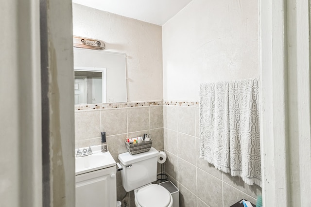 bathroom with vanity, toilet, and tile walls