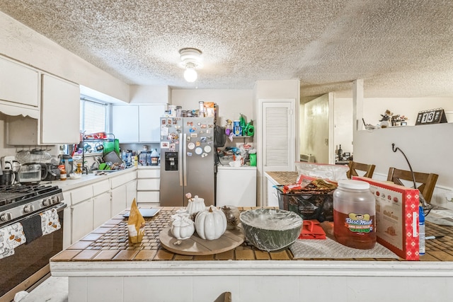 kitchen featuring washer / dryer, appliances with stainless steel finishes, a textured ceiling, and white cabinets