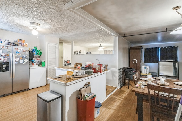 kitchen featuring light wood-type flooring, a textured ceiling, ceiling fan, stainless steel refrigerator with ice dispenser, and washer / clothes dryer