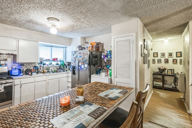 kitchen featuring light wood-type flooring, appliances with stainless steel finishes, a textured ceiling, and white cabinets