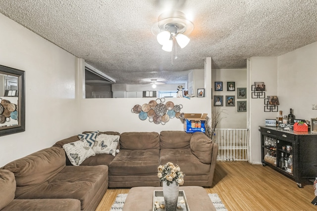 living room featuring a textured ceiling, ceiling fan, and light wood-type flooring