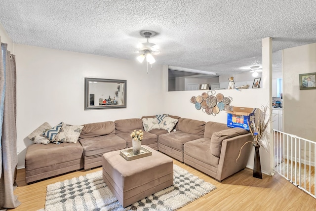 living room featuring ceiling fan, a textured ceiling, and light hardwood / wood-style flooring