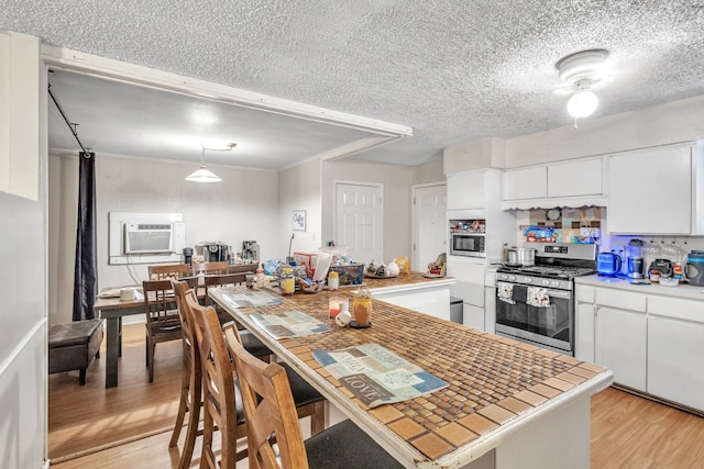 kitchen featuring a textured ceiling, light hardwood / wood-style flooring, stainless steel appliances, and white cabinetry