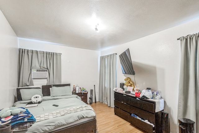 bedroom with a textured ceiling, cooling unit, and light hardwood / wood-style floors