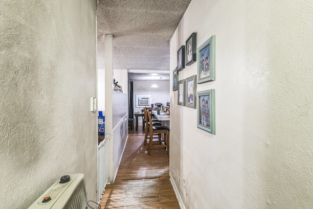 corridor featuring a textured ceiling and hardwood / wood-style floors