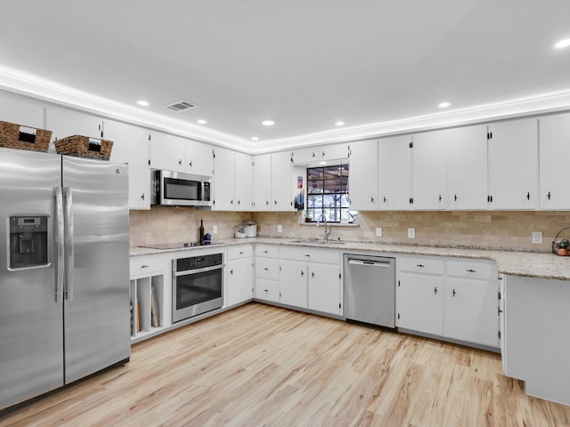 kitchen featuring decorative backsplash, appliances with stainless steel finishes, light wood-type flooring, sink, and white cabinets