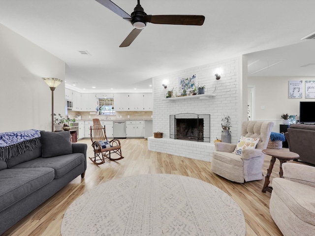 living room featuring a brick fireplace, ceiling fan, and light wood-type flooring