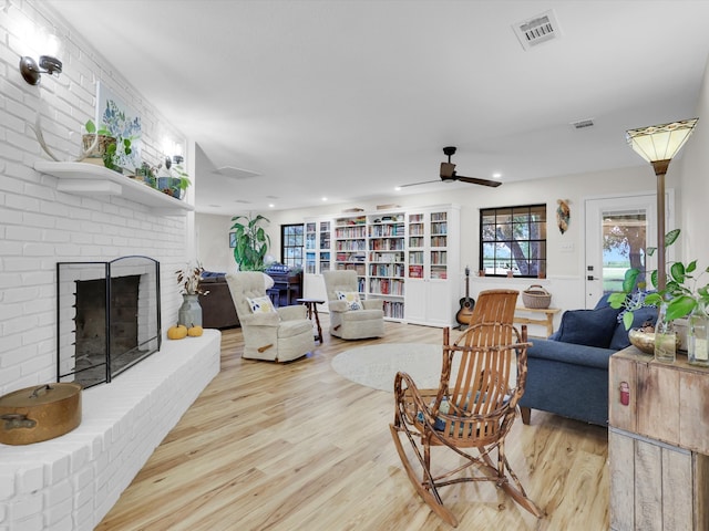 living room featuring a fireplace, light hardwood / wood-style floors, and ceiling fan