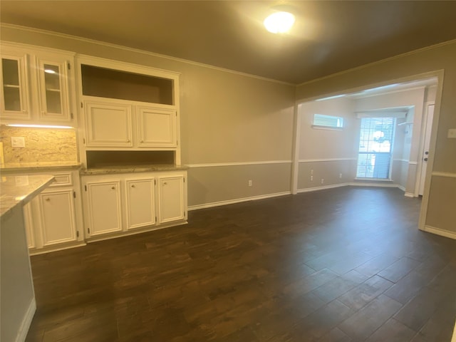 interior space with dark wood-type flooring, white cabinets, and ornamental molding