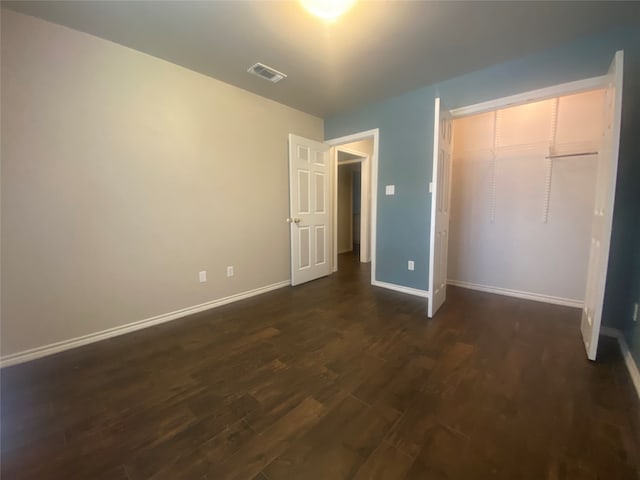 unfurnished bedroom with dark hardwood / wood-style flooring and a closet