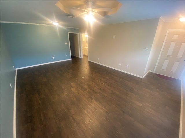 empty room with ceiling fan, visible vents, baseboards, ornamental molding, and dark wood-style floors