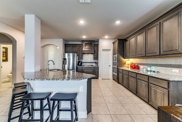 kitchen with stone countertops, backsplash, stainless steel appliances, sink, and custom exhaust hood