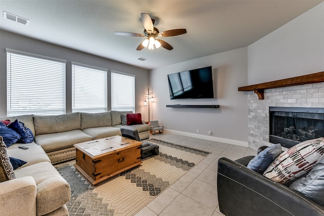 tiled living room featuring a brick fireplace and ceiling fan