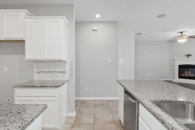 kitchen featuring light stone countertops, light tile patterned floors, white cabinets, and stainless steel dishwasher