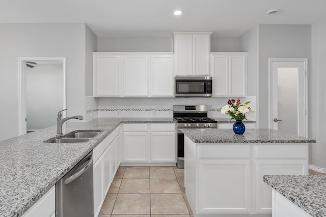 kitchen featuring backsplash, appliances with stainless steel finishes, sink, and light stone counters