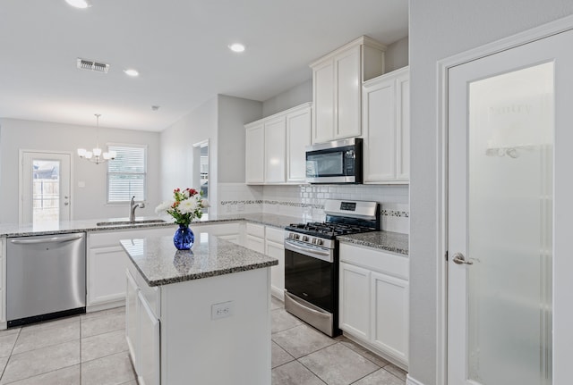 kitchen featuring stainless steel appliances, sink, kitchen peninsula, decorative light fixtures, and backsplash