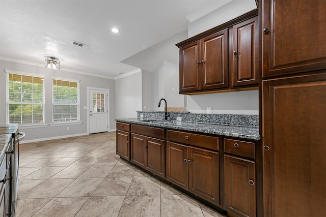 kitchen with dark brown cabinets, crown molding, sink, and dark stone counters