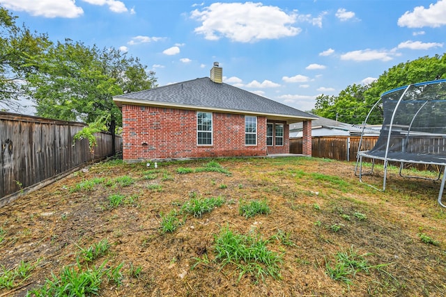 rear view of property featuring a trampoline