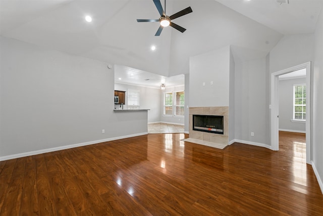 unfurnished living room with hardwood / wood-style floors, ceiling fan, plenty of natural light, and a high end fireplace