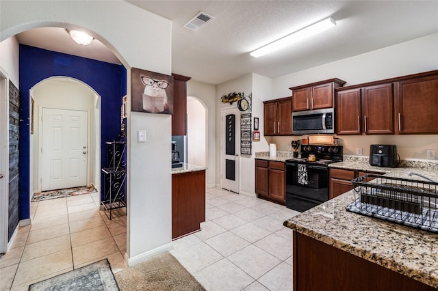 kitchen with visible vents, light stone counters, stainless steel microwave, black / electric stove, and light tile patterned flooring