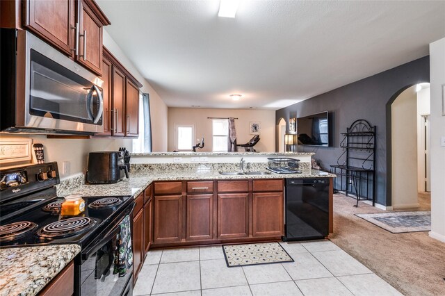 kitchen featuring black appliances, light stone countertops, kitchen peninsula, and sink