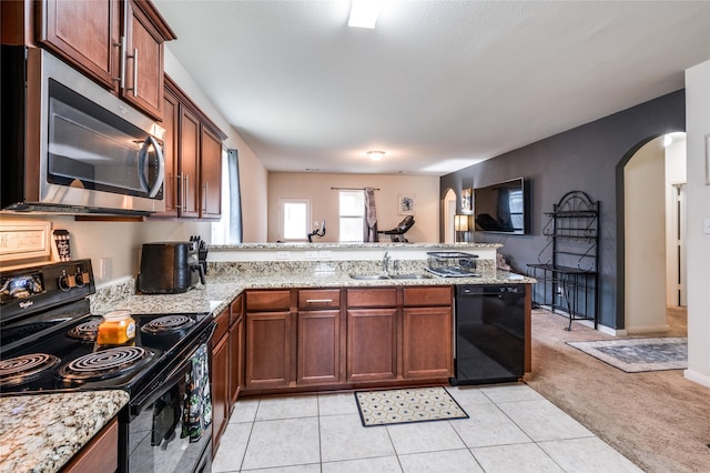 kitchen with light carpet, a peninsula, arched walkways, black appliances, and a sink