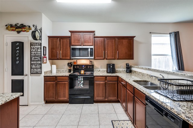 kitchen featuring light tile patterned floors, light stone countertops, black appliances, and a sink