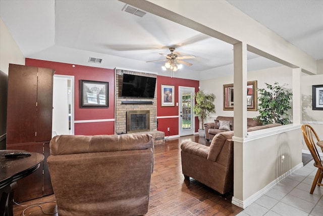 living room with light hardwood / wood-style flooring, a brick fireplace, and ceiling fan