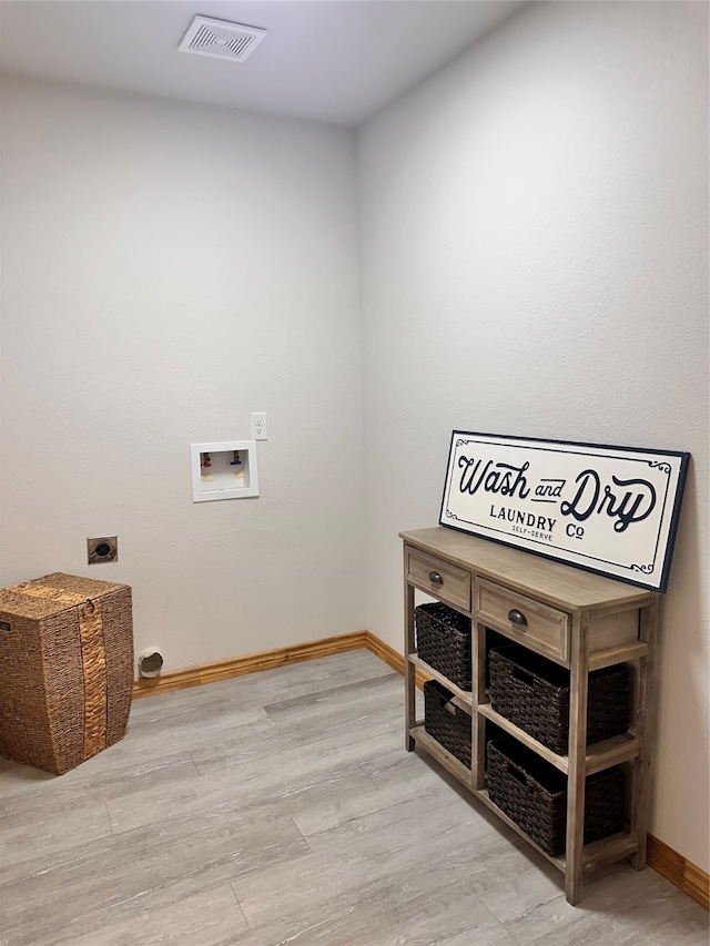 clothes washing area with hookup for a washing machine, light hardwood / wood-style floors, and electric dryer hookup