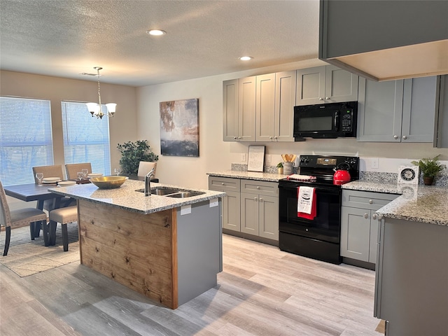 kitchen featuring a notable chandelier, light wood-type flooring, black appliances, and hanging light fixtures